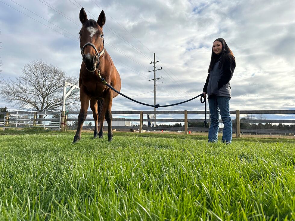 Kylie Ossege smiles while standing next to her horse, Blaze, at a boarding facility Saturday,...
