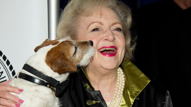 Betty White poses with Uggie the dog from the film 'The Artist' as she arrives for her Friars...